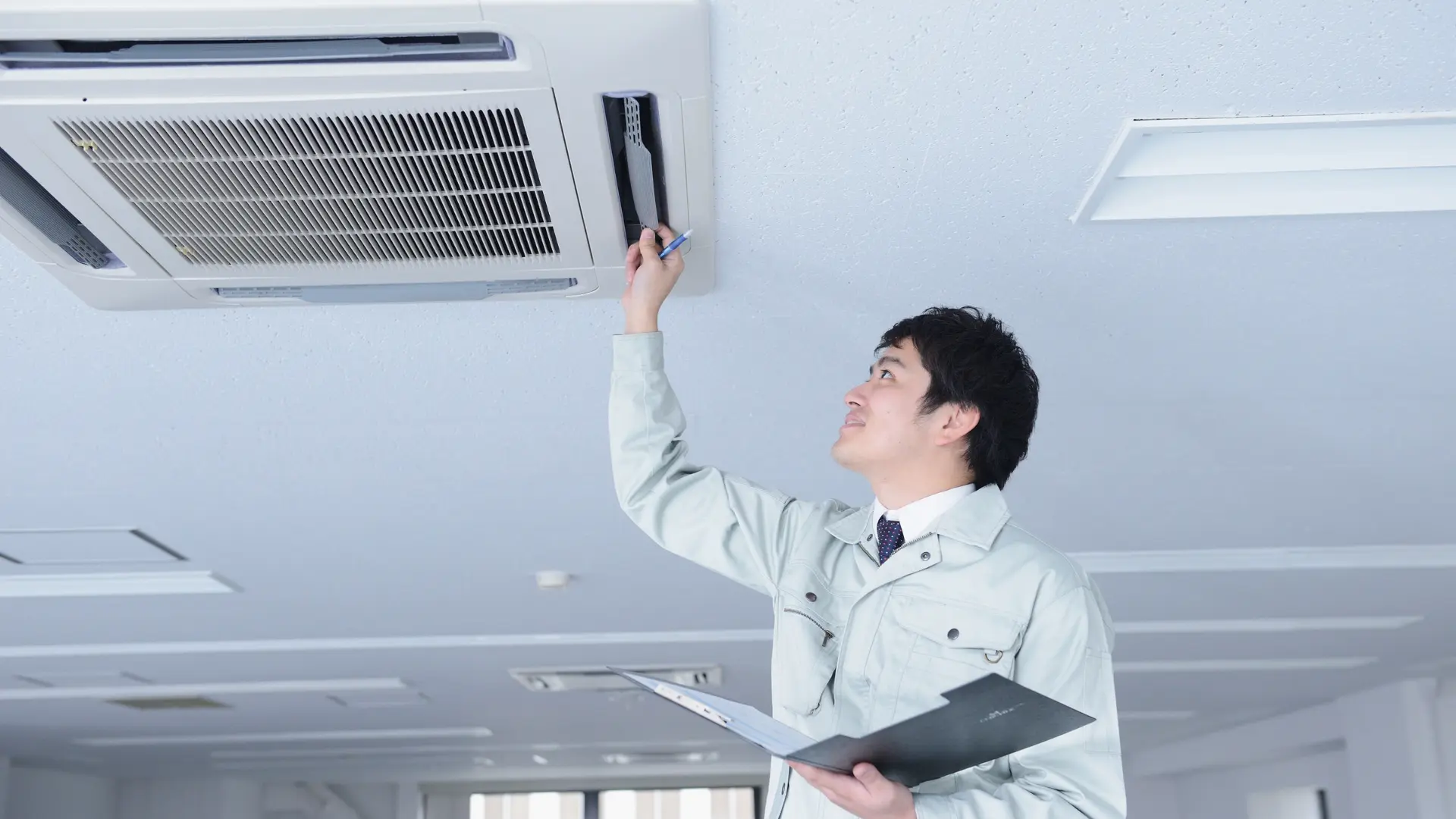 天井の空調機を確認する作業員